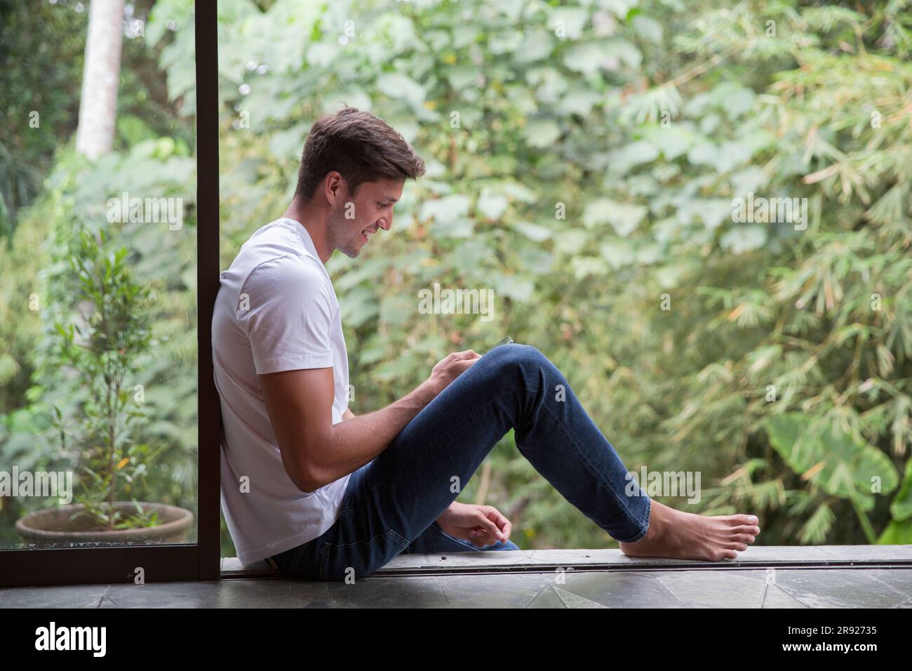 Happy young man using smart phone at home Stock Photo