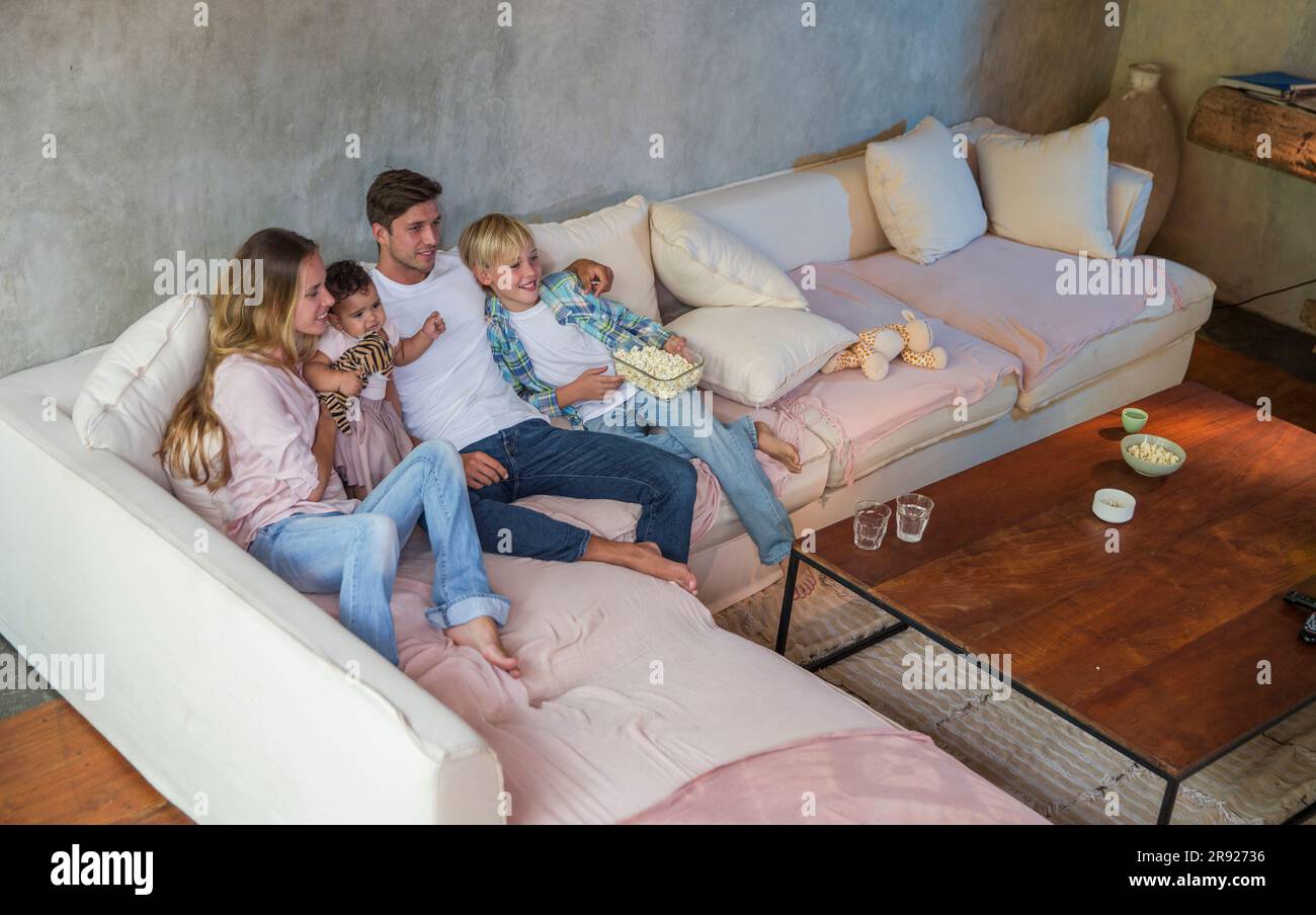 Happy family watching TV together at home Stock Photo