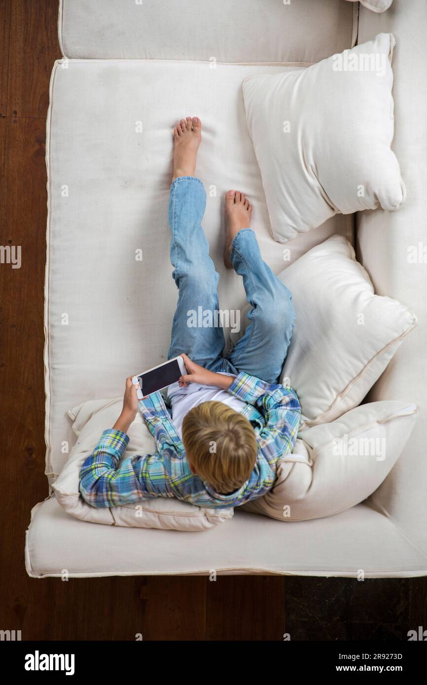 Boy using smart phone on sofa at home Stock Photo