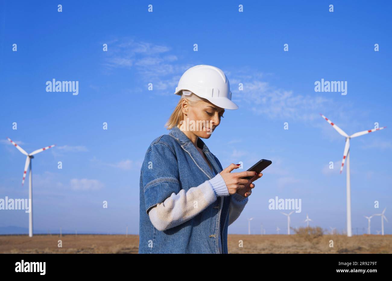 Engineer using smart phone standing in desert Stock Photo