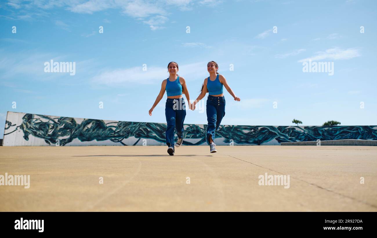 Happy girls holding hands and running on sunny day Stock Photo - Alamy