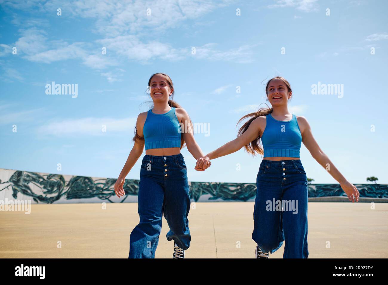 Happy girls holding hands and running in skateboard park Stock Photo ...