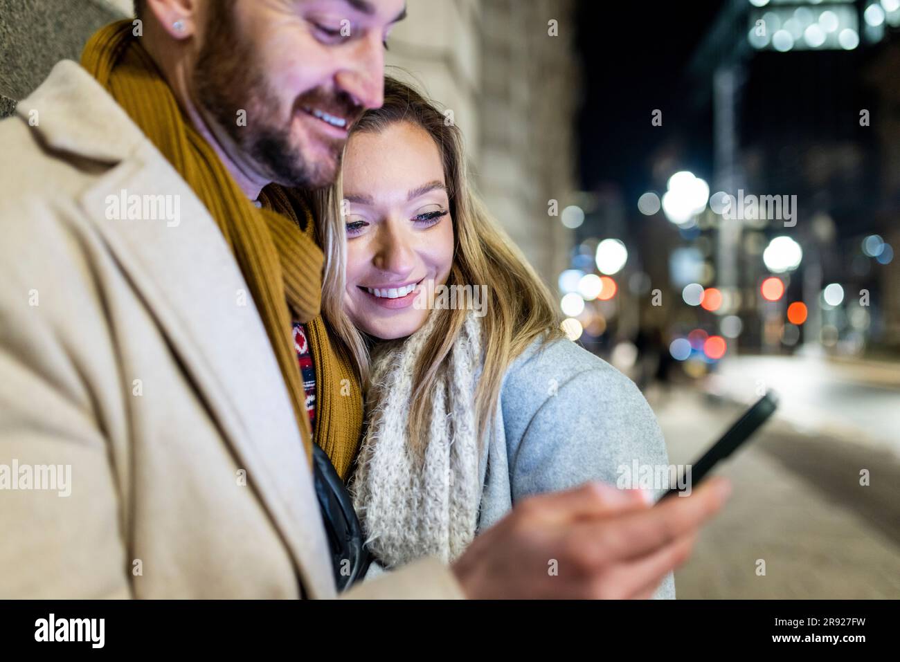 Happy young woman with man using smart phone Stock Photo