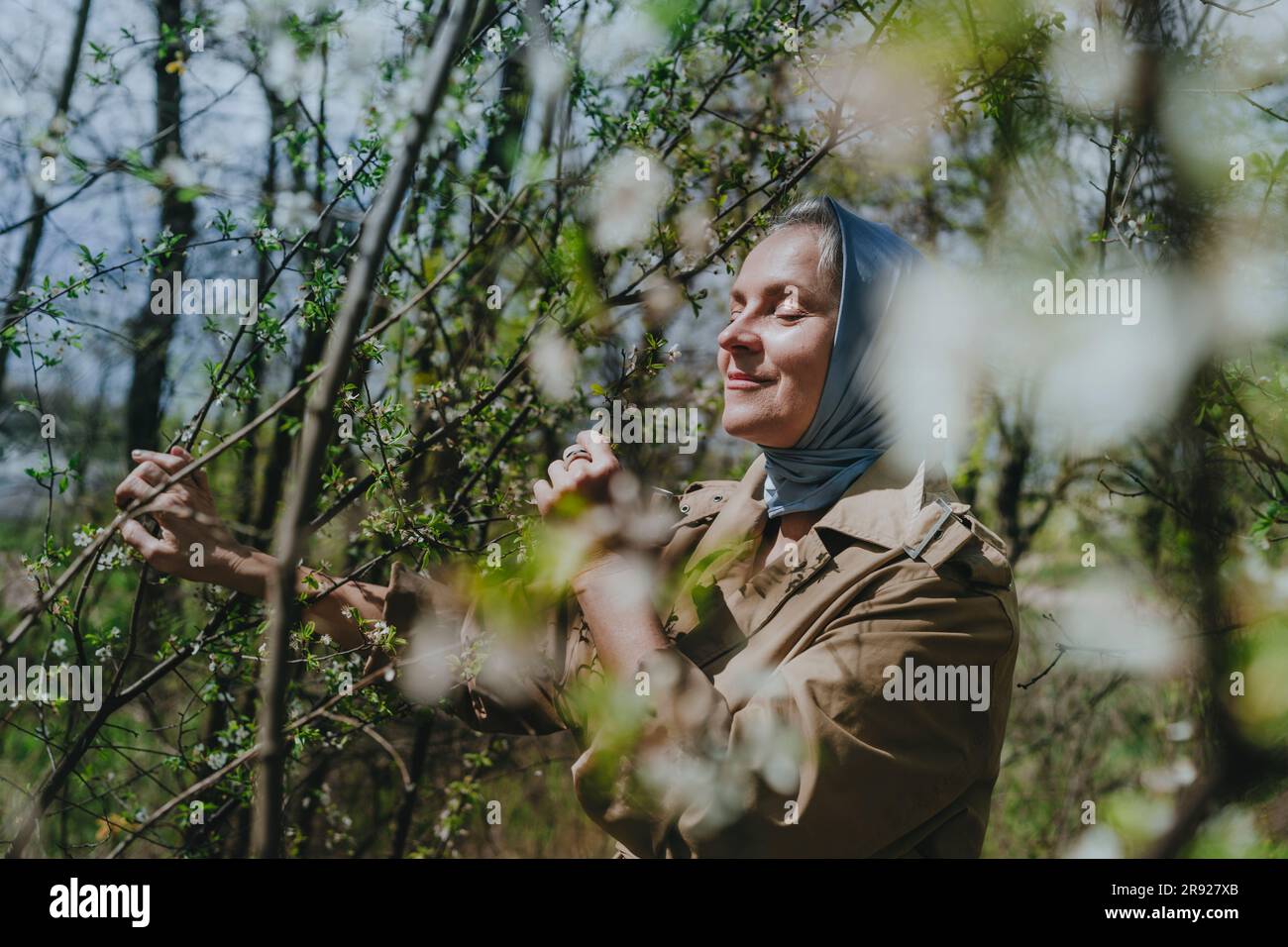 Mature woman smelling flowers at forest Stock Photo