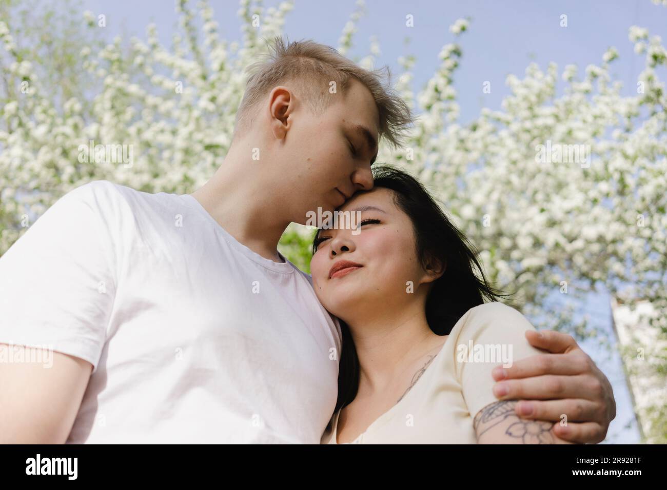 Young man kissing and embracing girlfriend at park Stock Photo