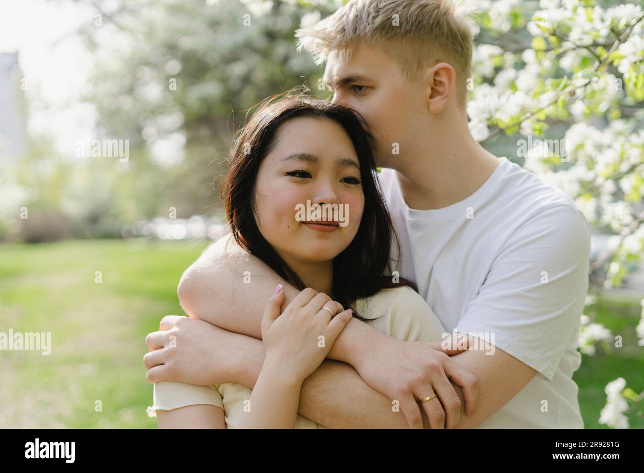 Young man embracing girlfriend at park Stock Photo