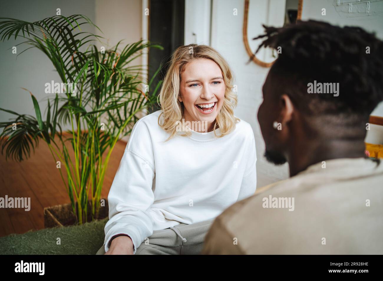 Happy young couple discussing and laughing at home Stock Photo