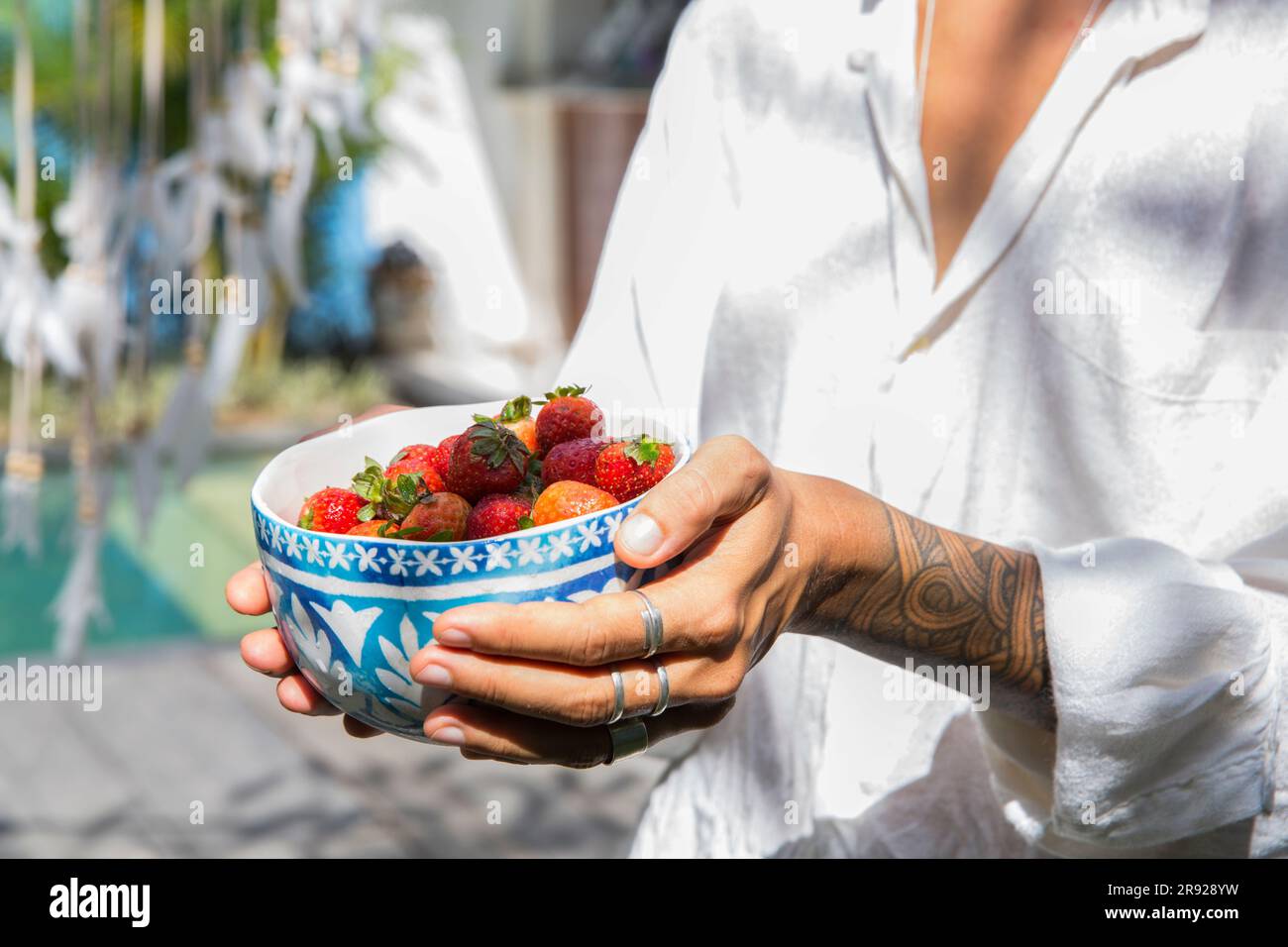 Woman holding fresh strawberries in bowl Stock Photo
