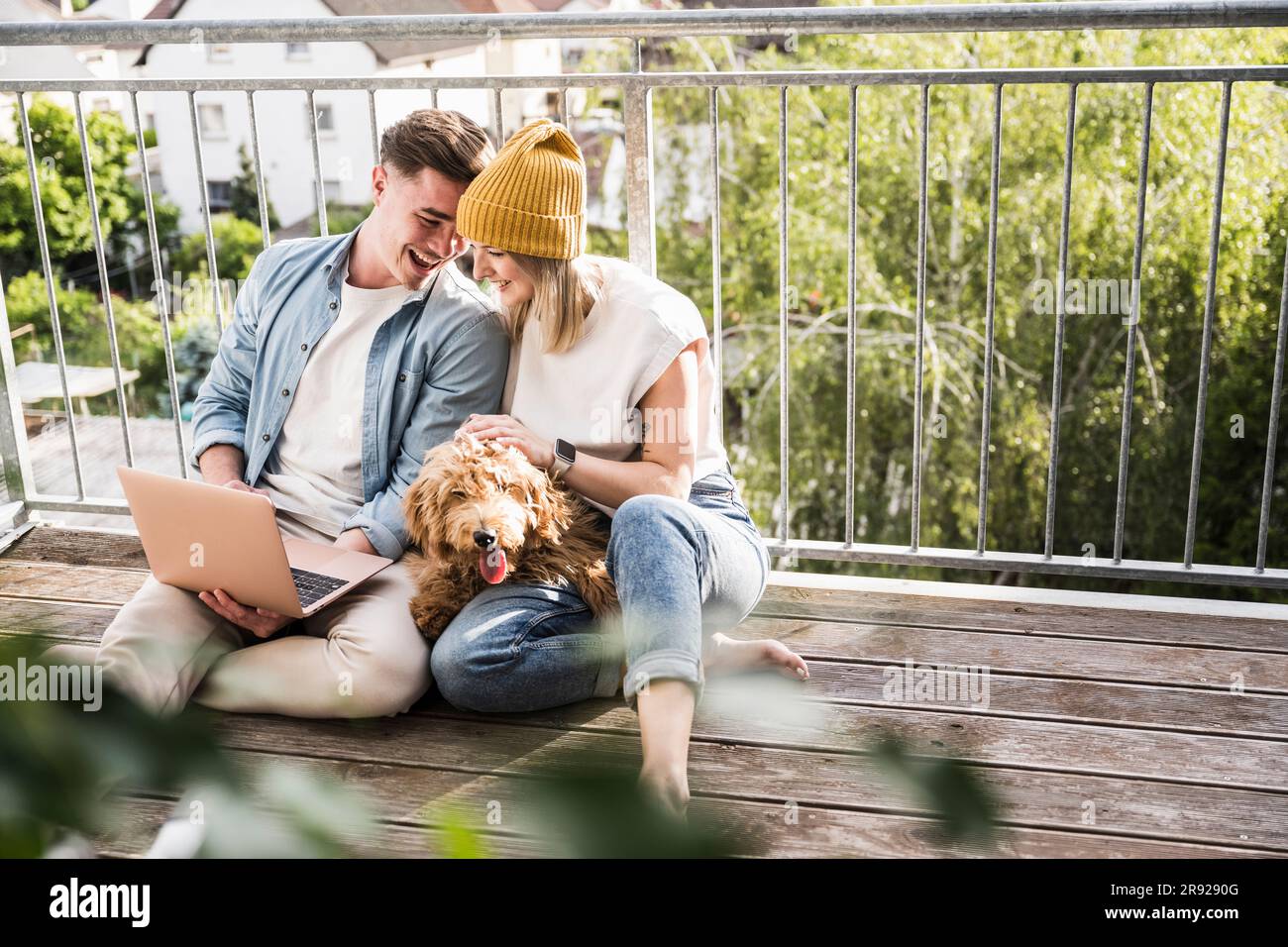 Loving young couple using laptop on balcony Stock Photo