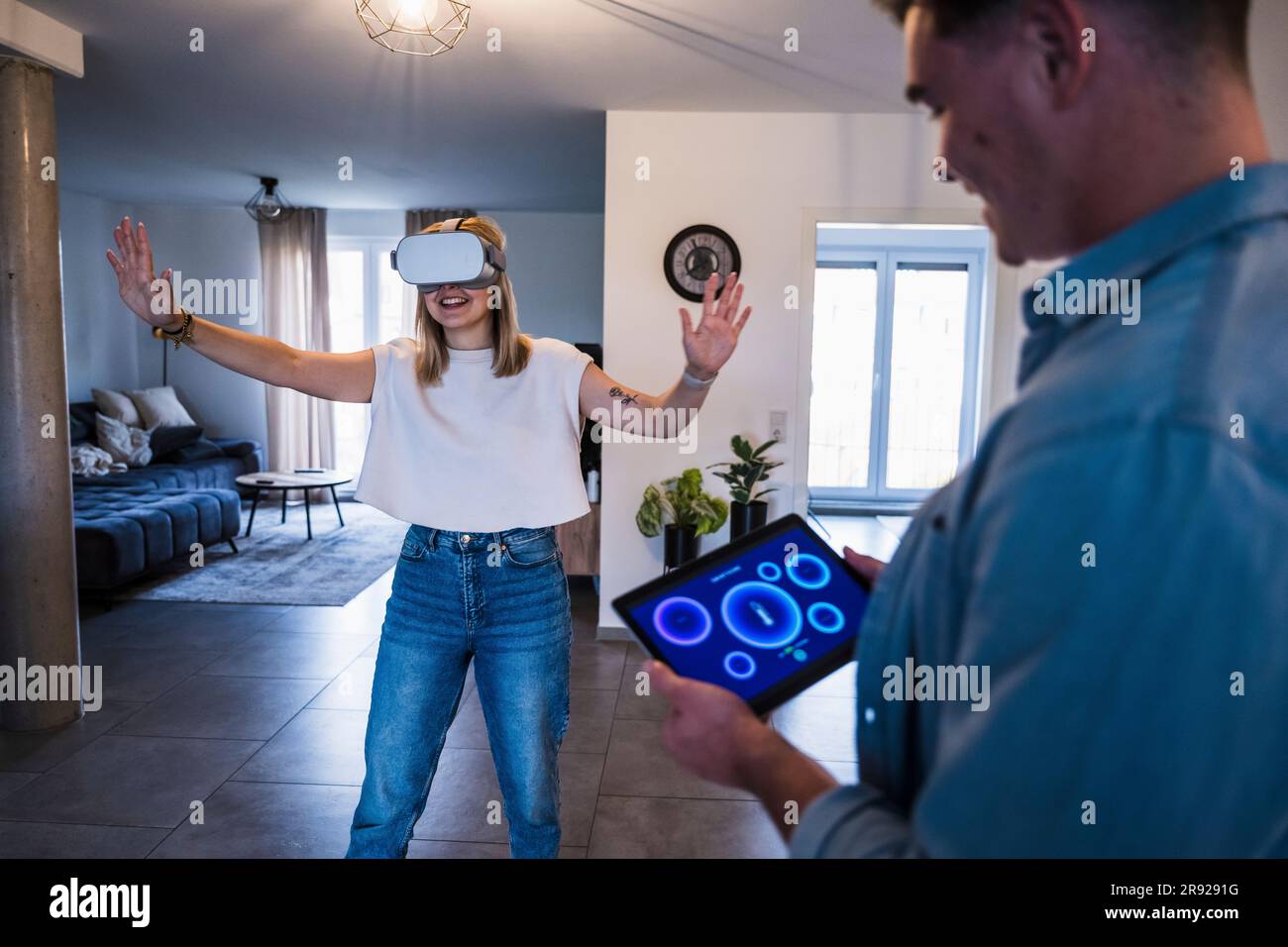 Man using tablet PC with woman wearing virtual reality simulator Stock Photo