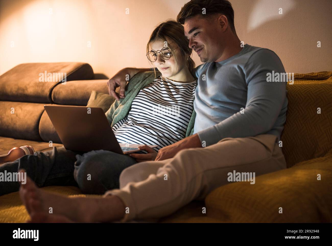 Smiling young couple using laptop together at home Stock Photo