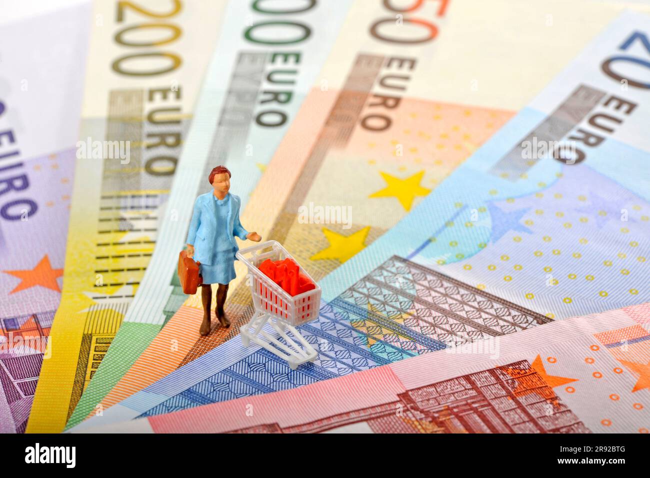 female retiree figurine with a full shopping cart on euro banknotes Stock Photo