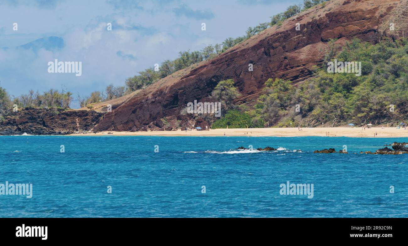 sandy beach in front of large lava rock with deep blue sea, few holidaymakers bathing on golden sandy beach, USA, Hawaii, Maui, Kihei Stock Photo