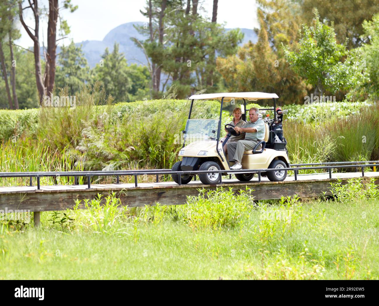 Golf cart, old couple or golfers driving on field in fitness workout or exercise on green course together. Mature male driver, senior woman golfing or Stock Photo