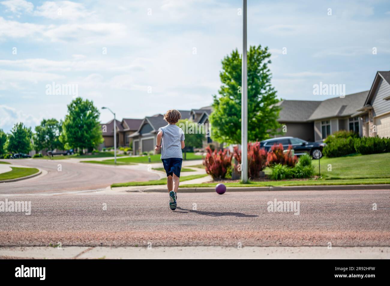 Chasing a ball that has crossed the street by rolling into a road Stock