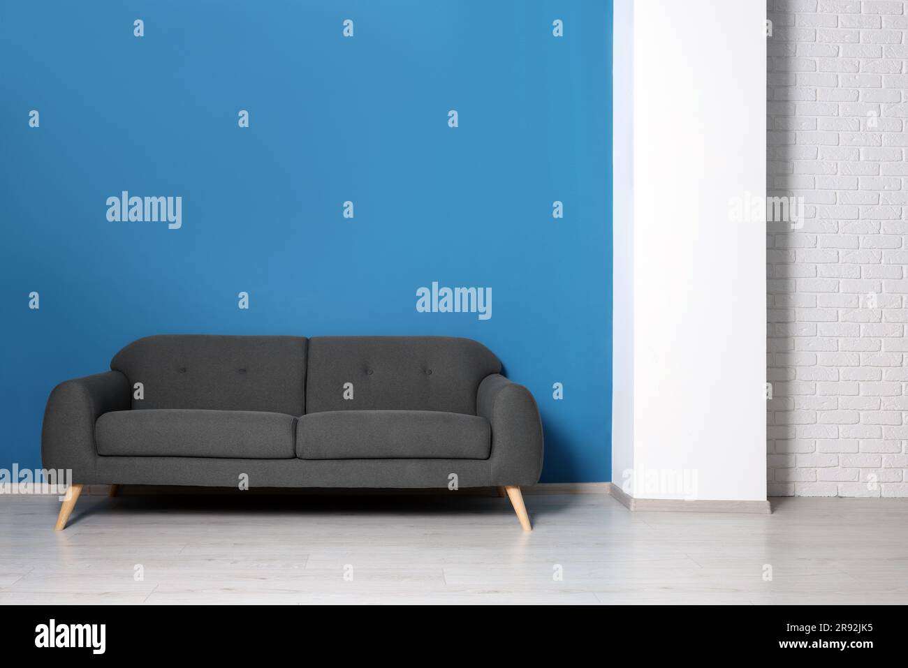 Stylish grey sofa near blue wall in room. Interior design Stock Photo ...