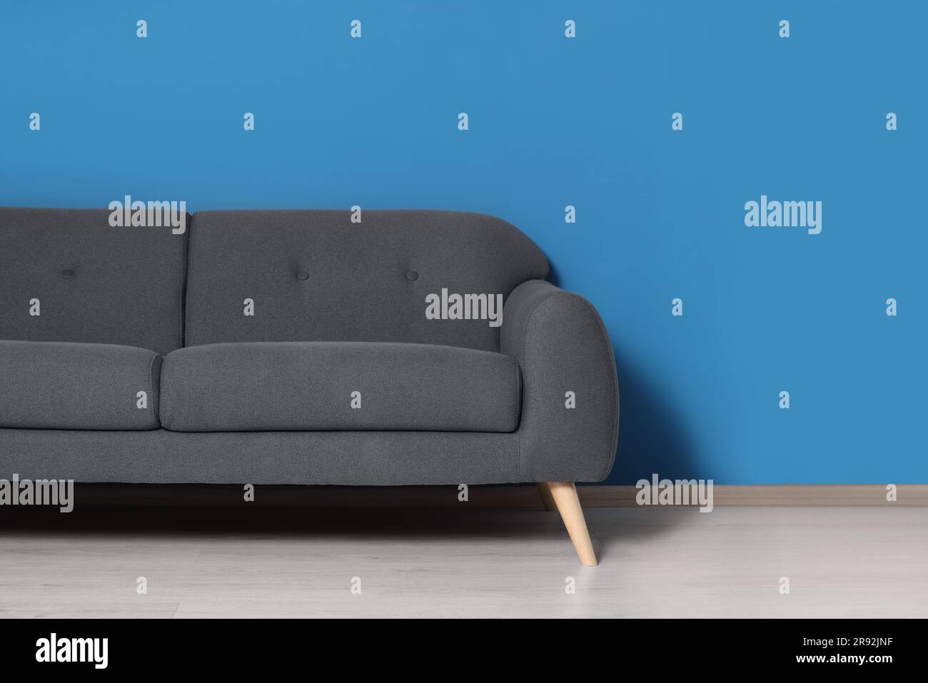 Stylish grey sofa near blue wall in room. Interior design Stock Photo ...