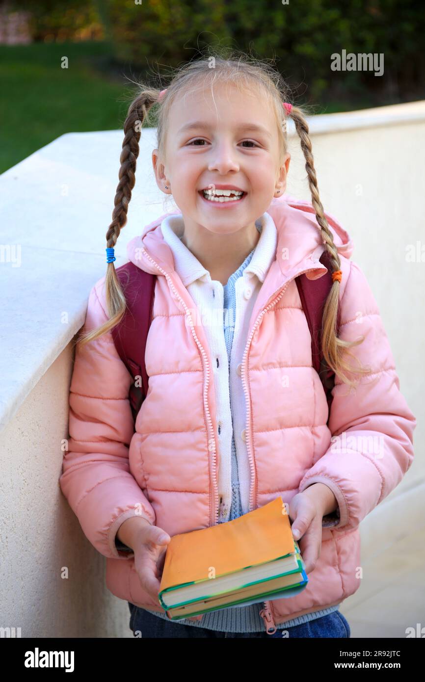 Cute little girl with backpack and textbooks outdoors Stock Photo - Alamy