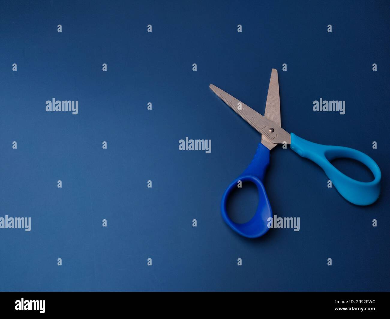 Closeup blue scissors on a blue background with copy space Stock Photo