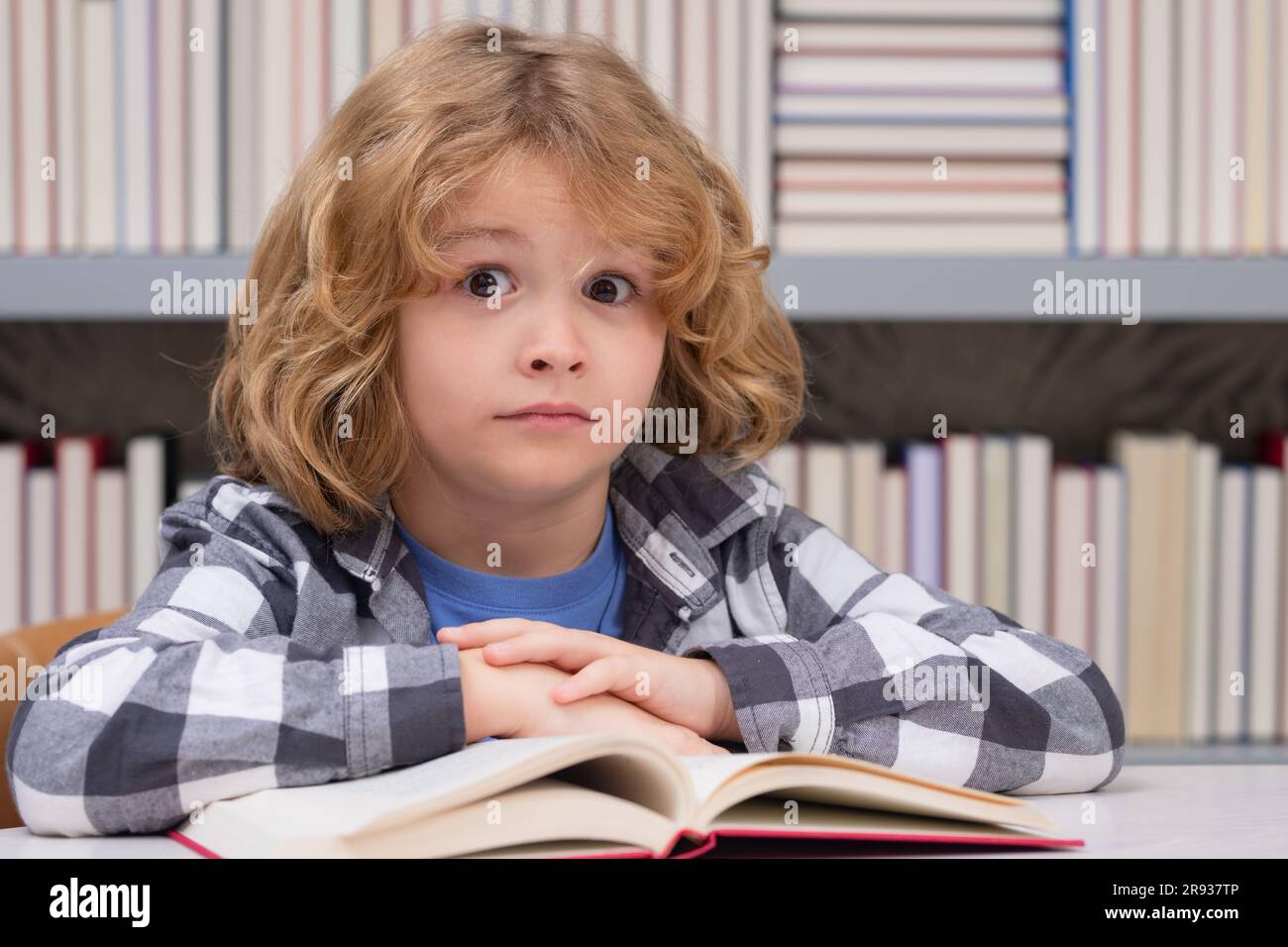 Childhood and education concept. Kid reading a book in a school library