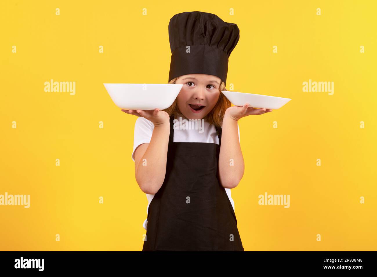 Little cook with cooking plate. Kid chef cook, studio portrait