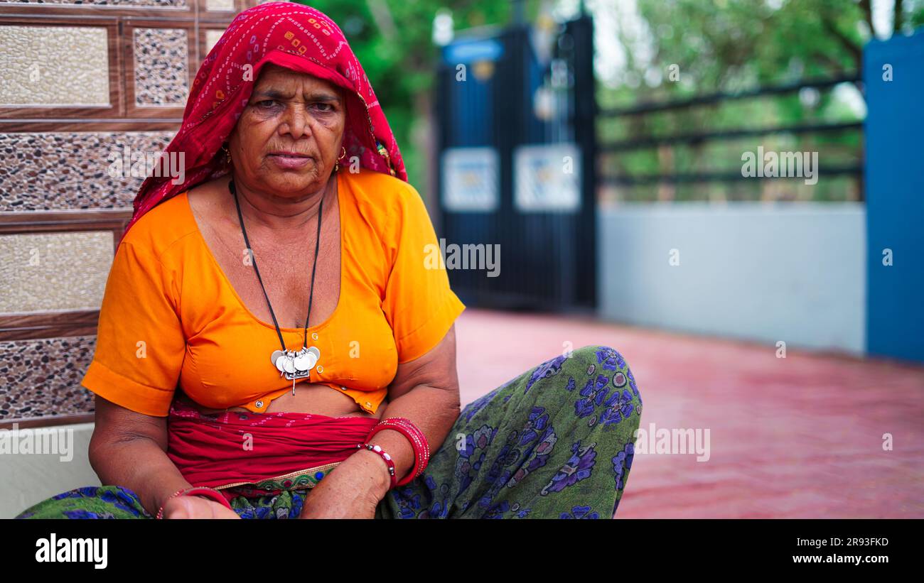 Portrait of Indian Senior woman sitting near main entrance and looking at camera. Stock Photo