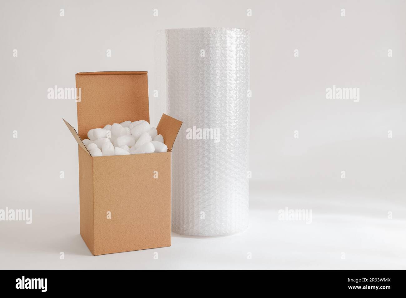 Cardboard box isolated on the white background filled with packing peanuts and bubble wrap Stock Photo
