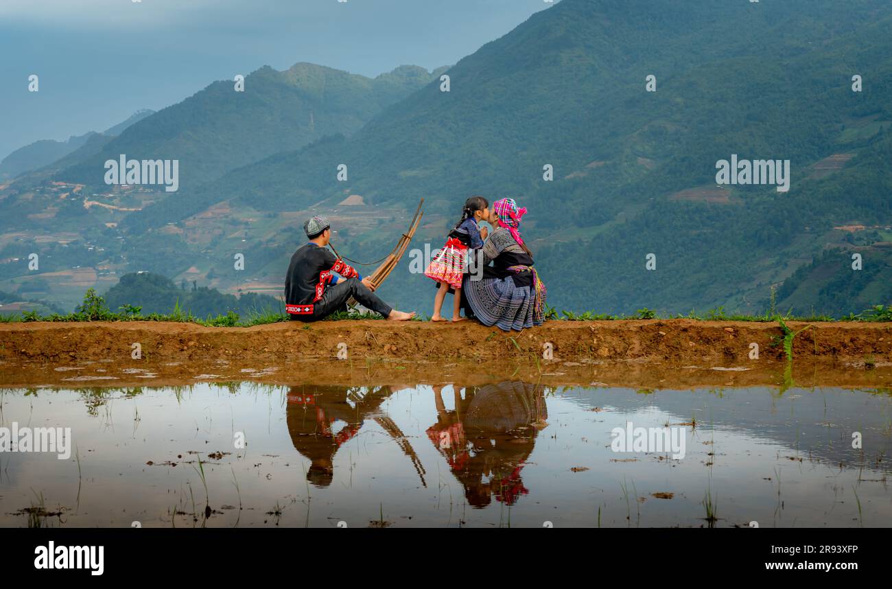 A young H'mong family relaxes by a terraced field in Mu Cang Chai, Yen Bai Province, Vietnam Stock Photo