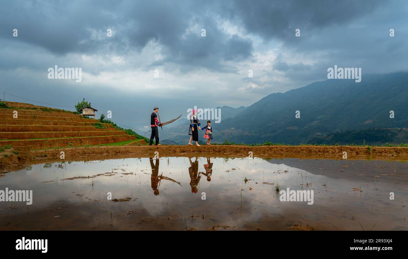 A young H'mong family relaxes by a terraced field in Mu Cang Chai, Yen Bai Province, Vietnam Stock Photo