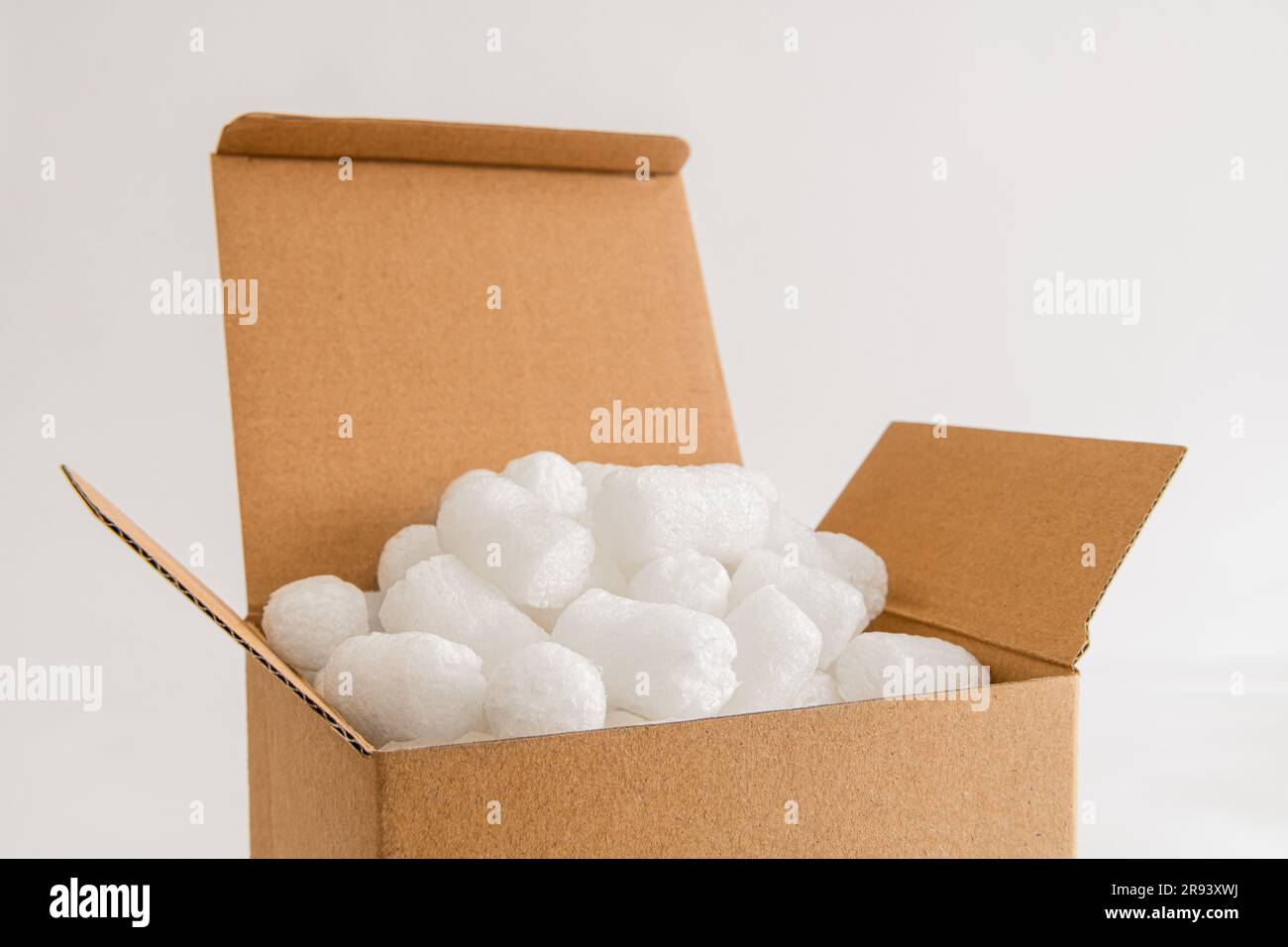 Cardboard box isolated on the white background filled with packing peanuts Stock Photo