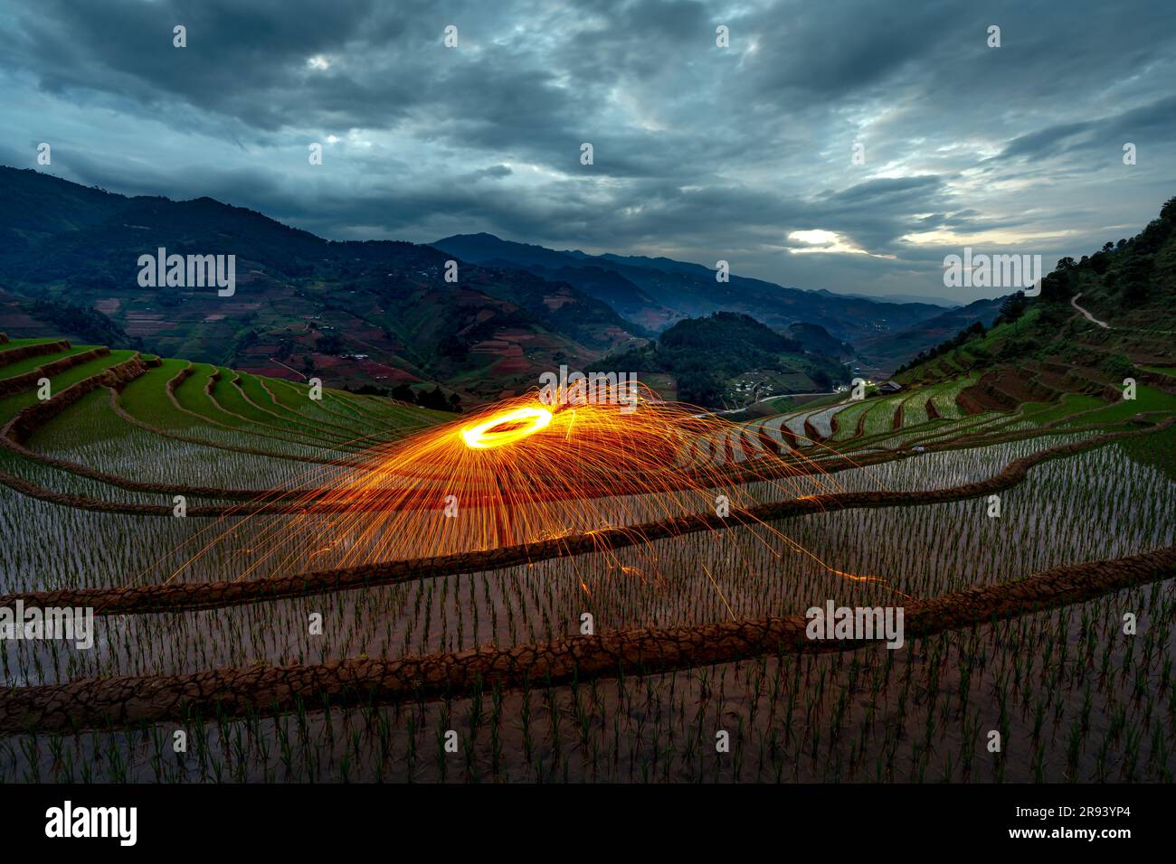 Burning steel wool spinning. Showers of glowing sparks from spinning steel wool on terraces field at dawn in Mu Cang Chai, Yen Bai province, Vietnam Stock Photo