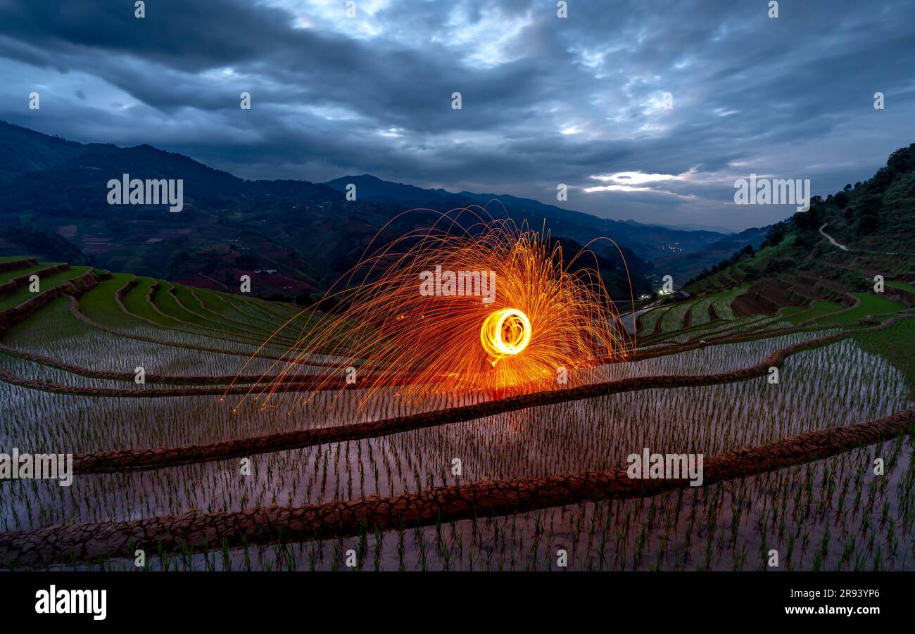Burning steel wool spinning. Showers of glowing sparks from spinning steel wool on terraces field at dawn in Mu Cang Chai, Yen Bai province, Vietnam Stock Photo