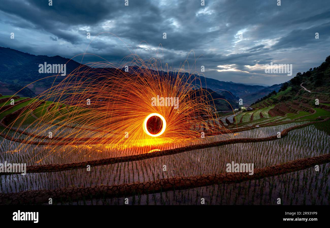 Burning steel wool spinning. Showers of glowing sparks from spinning steel wool on terraces field at dawn in Mu Cang Chai, Yen Bai province, Vietnam Stock Photo