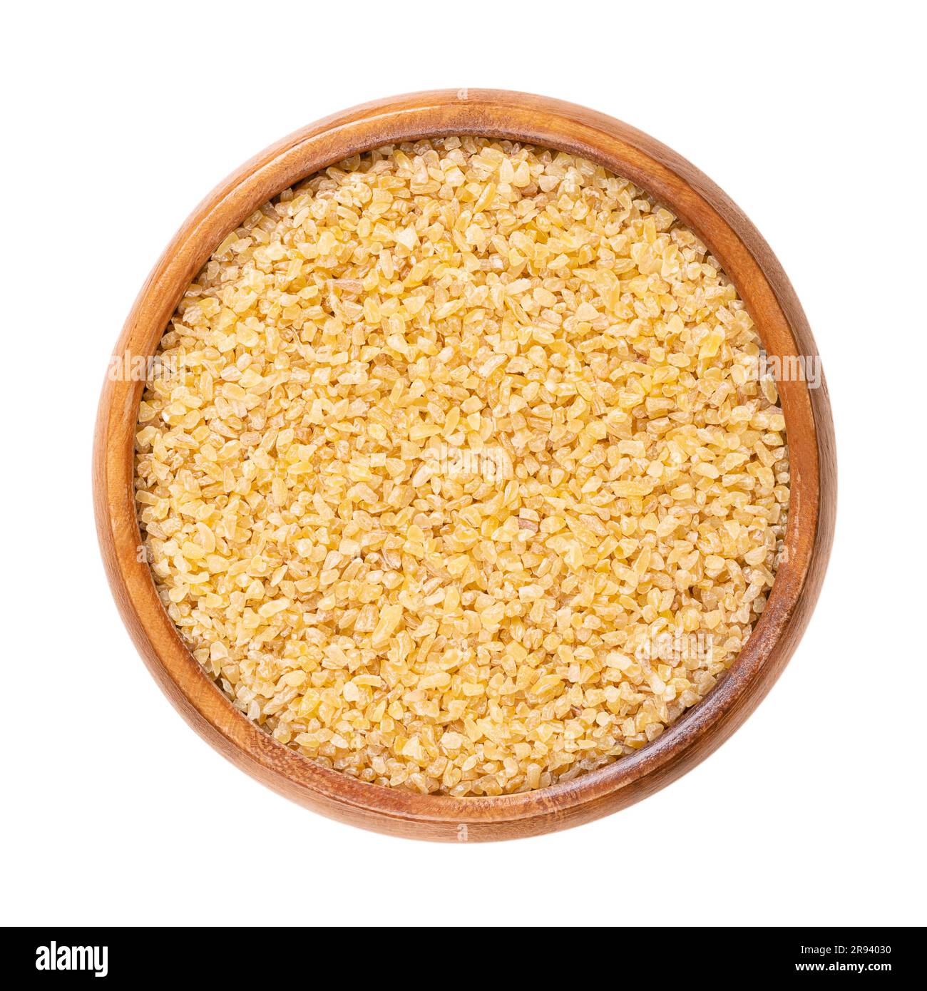 Coarse bulgur, also called burghul, in a wooden bowl. Cracked and parboiled wheat foodstuff, and a common ingredient in many cuisines of West Asia. Stock Photo