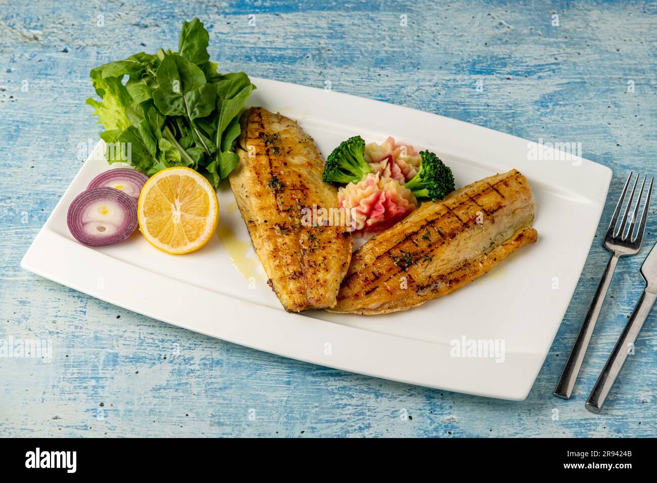 Grilled sea bass fillet served with garnishes in a fine dining