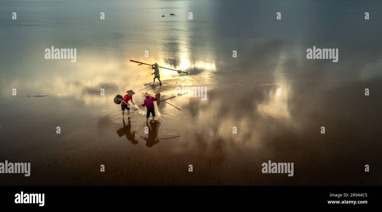 The image of fishermen in the fishing village using homemade tools to clams rake at sea at dawn Stock Photo