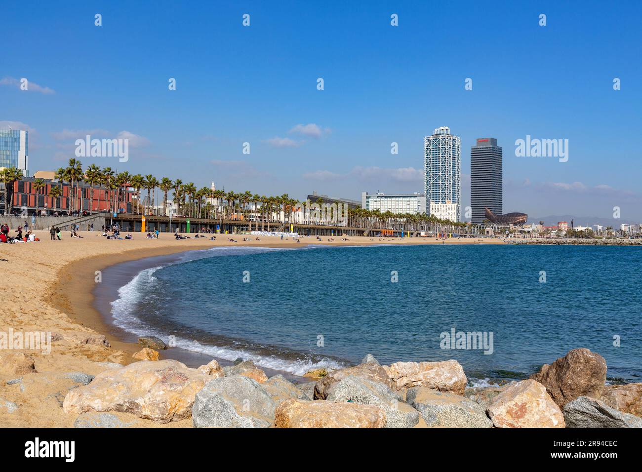 Barcelona, Spain - FEB 10, 2022: Buildings and people along the Barceloneta beach in Ciutat Vella district of Barcelona, the Mediterranean coast, Spai Stock Photo