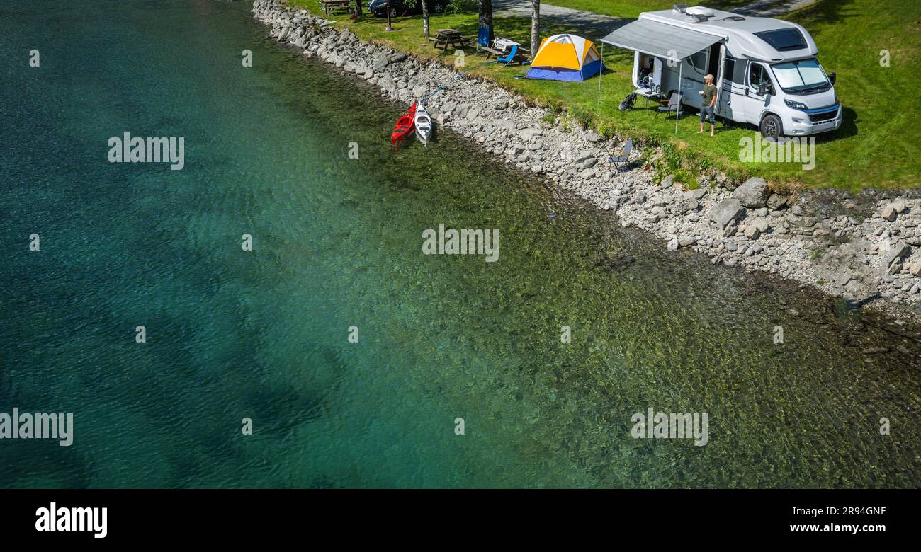 Aerial View of a Water Front RV Park. Camper Van and a Tent Next to Crystal Clear Glacial River Stock Photo
