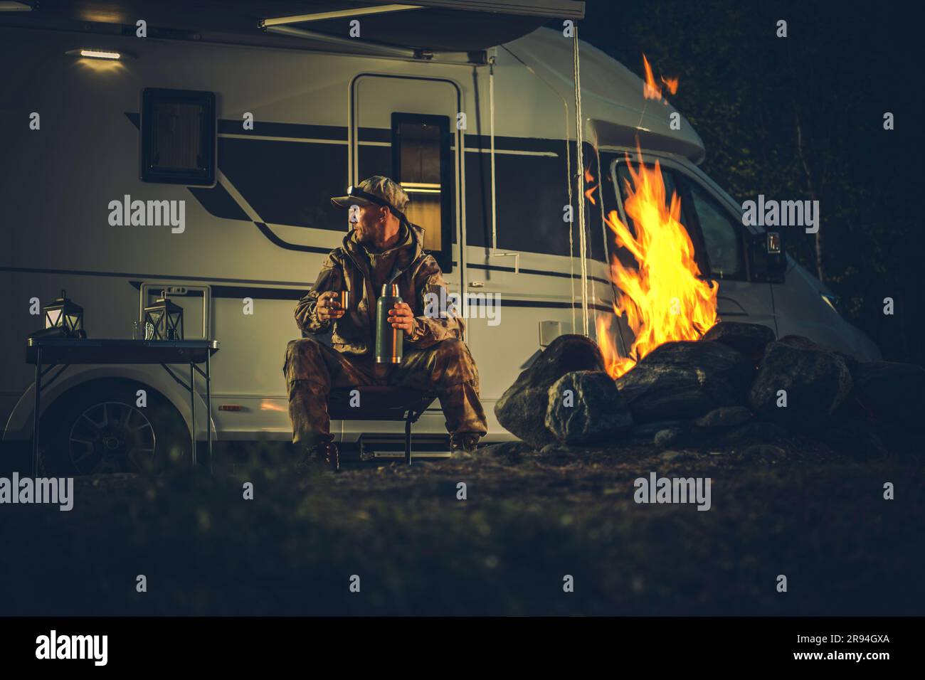 Hunter Wearing Camouflage Coating Burning Campfire Next to His