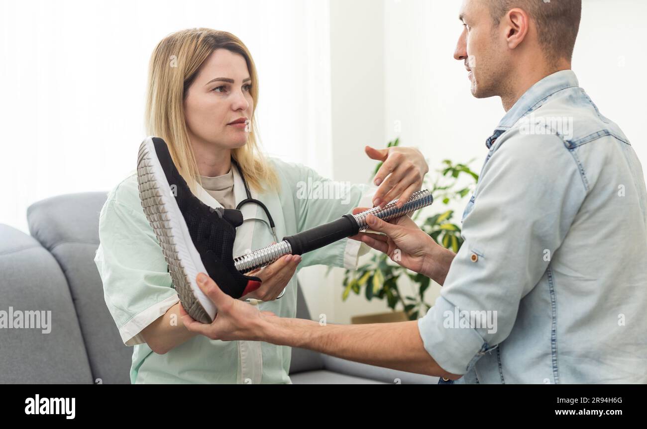 Modern Hospital Physical Therapy: Helps Disabled Patient Wearing Advanced Robotic Legs. Physiotherapy Rehabilitation Technology Stock Photo