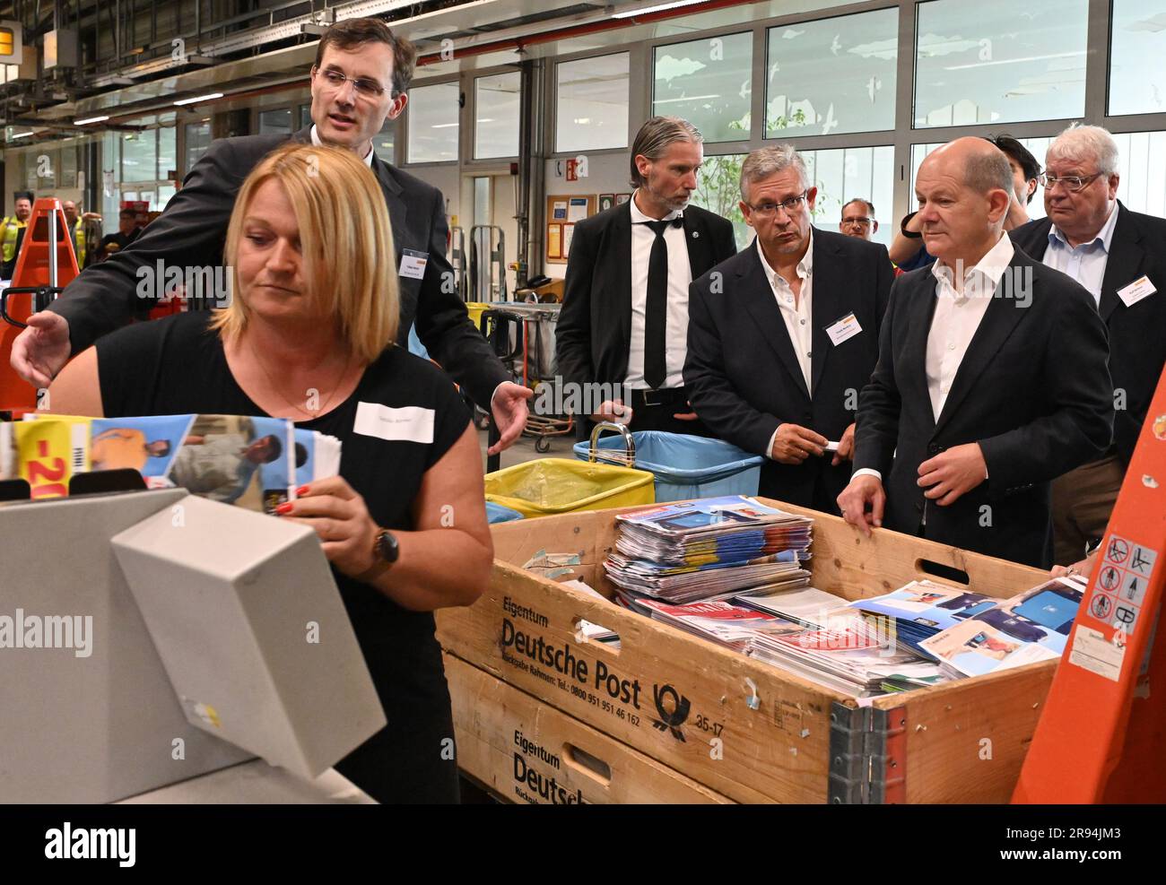 Stahnsdorf, Germany. 24th June, 2023. Tobias Meyer CO Deutsche Post AG (l) explains to Chancellor Olaf Scholz (SPD, 2nd from right), at Deutsche Post's mail center in Stahnsdorf how the large letter sorting system works. While there, the chancellor familiarized himself with the modern sorting equipment and learned about the possibilities of delivery using electric vehicles. Credit: Bernd Settnik/dpa/Alamy Live News Stock Photo