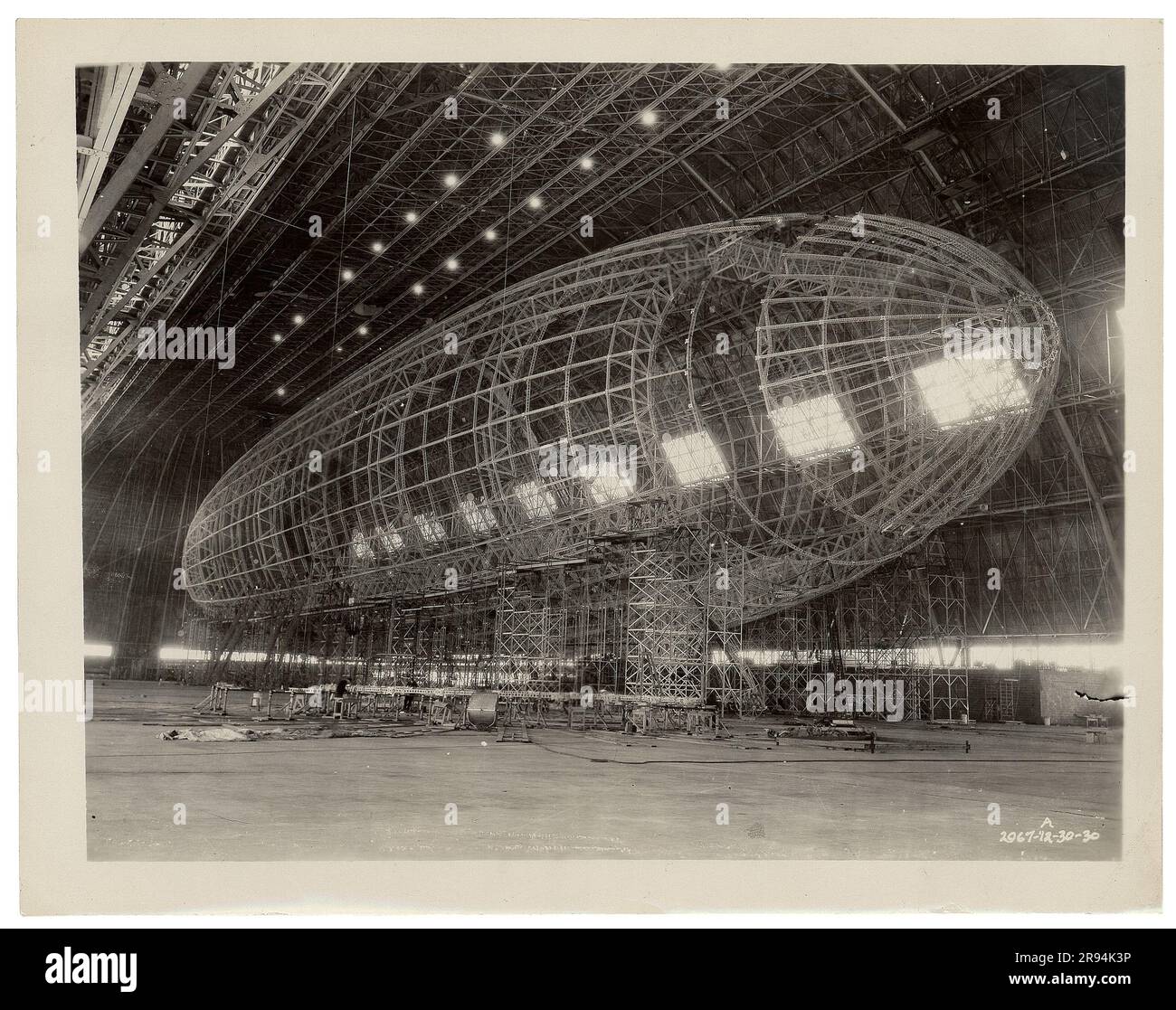 Nose section being attached to nearly completed framework. Original caption: Nose section being attached to USS Akron..Dirigible Disasters Stock Photo