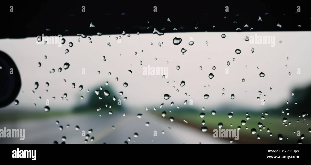 Rain shower on car windshield or car window and blurry road in