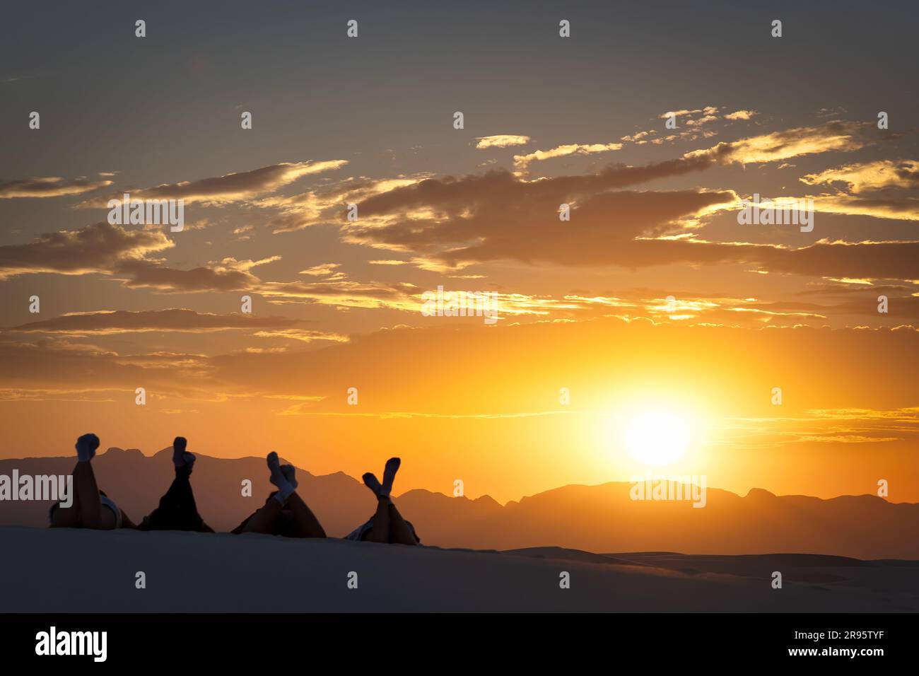People watching the sun set over the mountains at White Sands National Park near Alamogordo, New Mexico. Stock Photo
