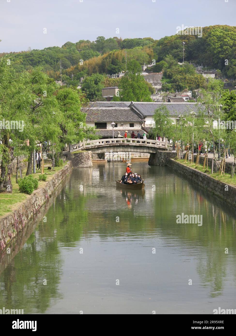 Punts with boatmen in traditional costume provide a leisurely sail along the canal for tourists to the quaint old town of Kurashiki, Japan. Stock Photo