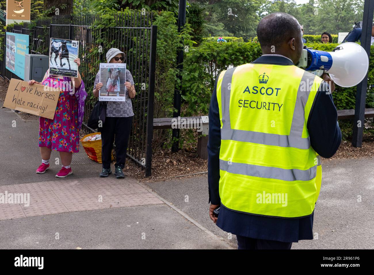 Ascot, UK. 24th June, 2023. An Ascot security guard uses a loudhailer to drown out two animal rights campaigners protesting outside Ascot racecourse as racegoers arrive for the fifth day of Royal Ascot. 28 horses died in jumps and flat races at Ascot between 2012-2022. Credit: Mark Kerrison/Alamy Live News Stock Photo