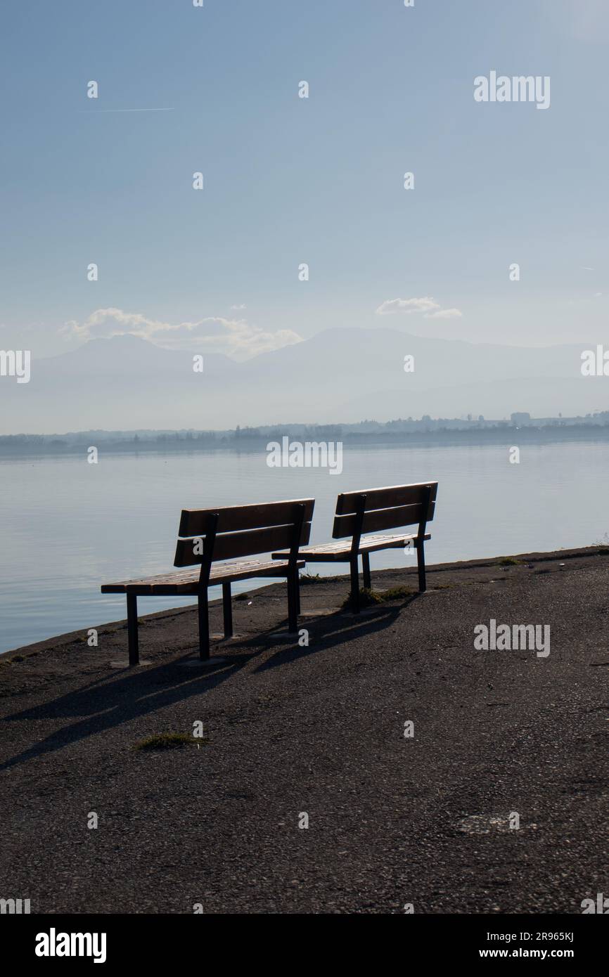 A vertical shot of Two wooden benches positioned on a beach in front of ...