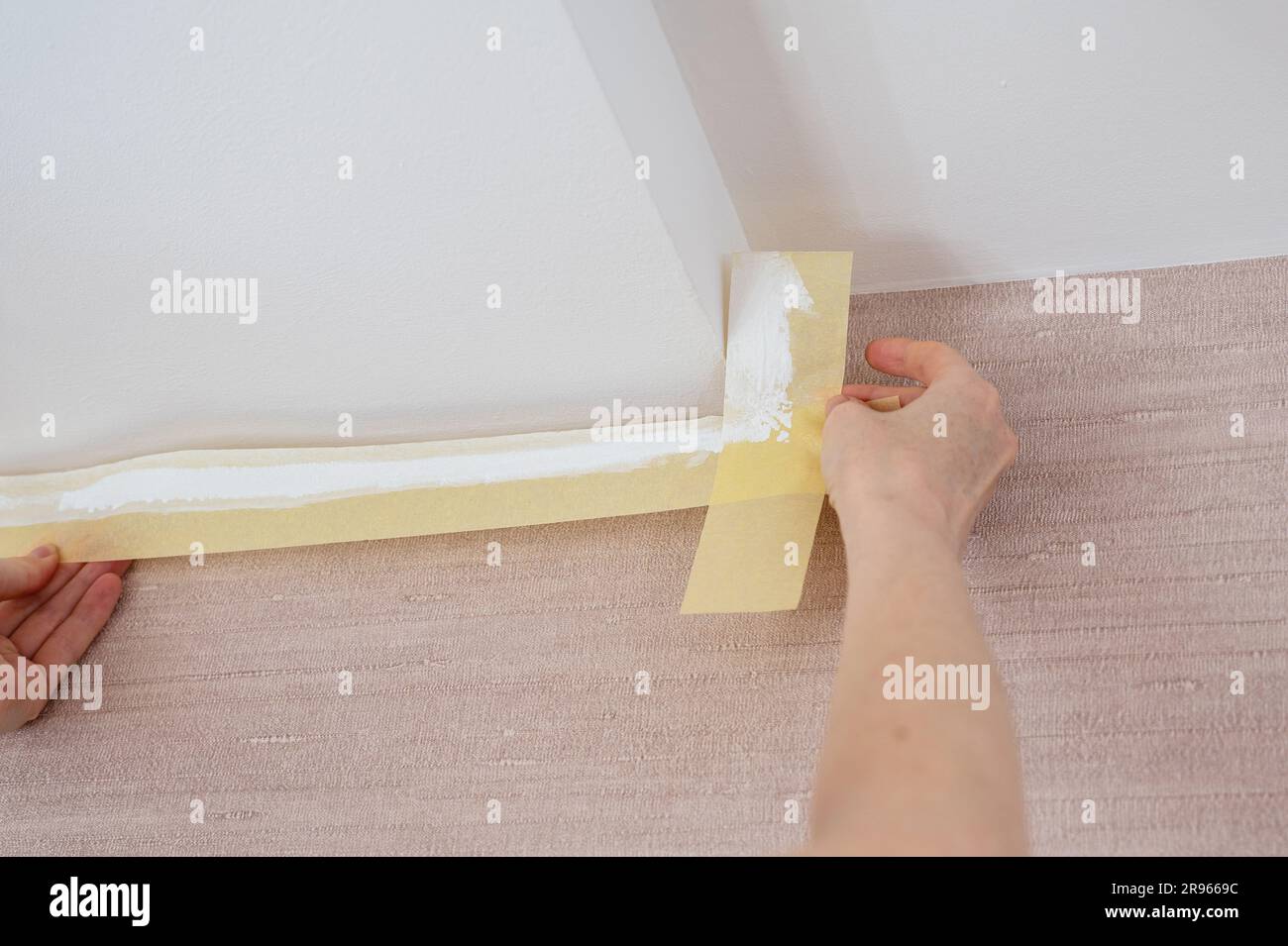 Removing masking tape after painting the ceiling in a room Stock Photo