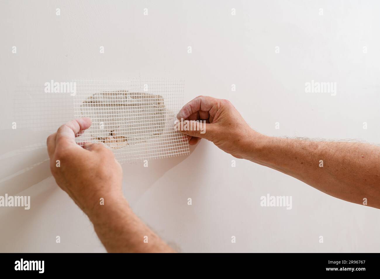 Repairing holes in drywall. A handyman is repairing a hole in the