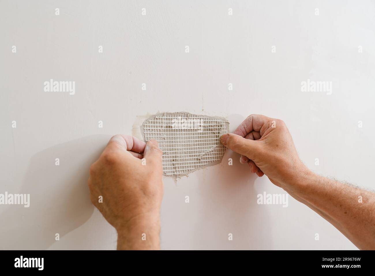 Repairing holes in drywall. A handyman is repairing a hole in the